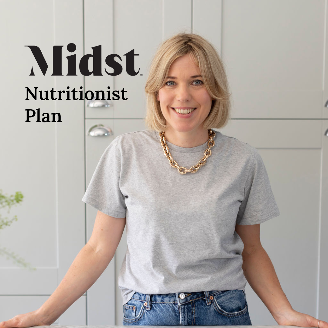 Amanda Duncan Midst Nutritionist, standing in a kitchen, smiling at the counter wearing a grey t-short and jeans. Blonde lair to her shoulders, blue eyes, and wearing a gold necklace.
