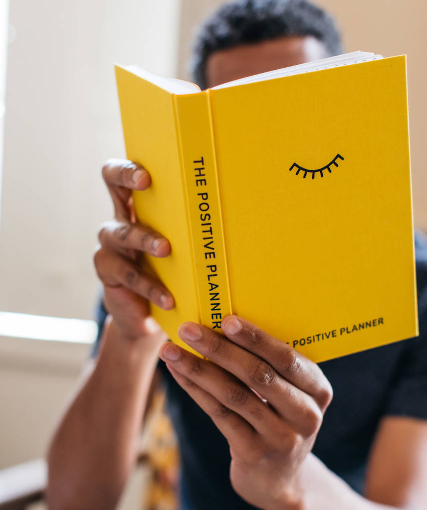 Person with brown skin holding up the journal to read