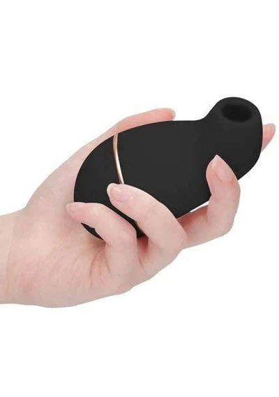 Black air vibrator in the palm of an adults hand. It fits in the middle of the palm and forefinger can curve along its shape , with the hole facing upwards.